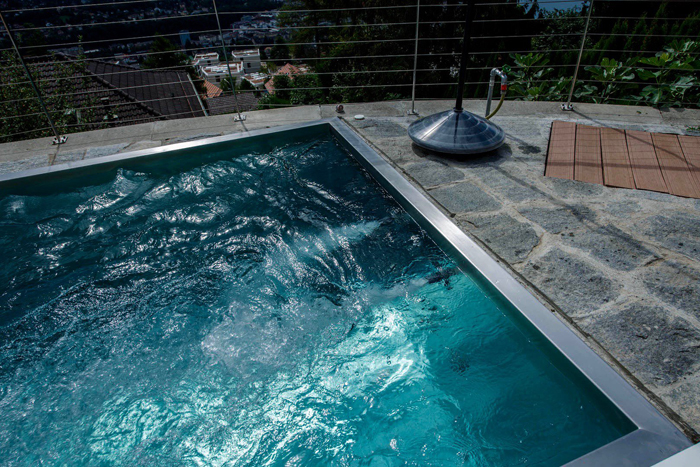 Piscine en inox qui s'accorde parfaitement avec un environnement naturel en pierre 